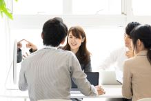 パソコンの周りに４人程度の人が集まり、コラボレーションをしながら仕事をしている