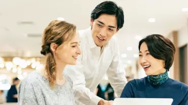 ラップトップを囲んで笑顔で協力する3人。