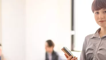 オフィスで携帯電話を持つ女性。