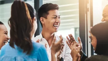 Group of people smiling and clapping in an office.