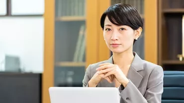 Businesswoman sitting at a desk with a laptop, looking professional.